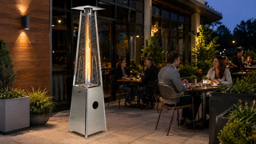 Stainless steel Legacy Heating flame patio heater warming guests on an outdoor restaurant terrace at night.
