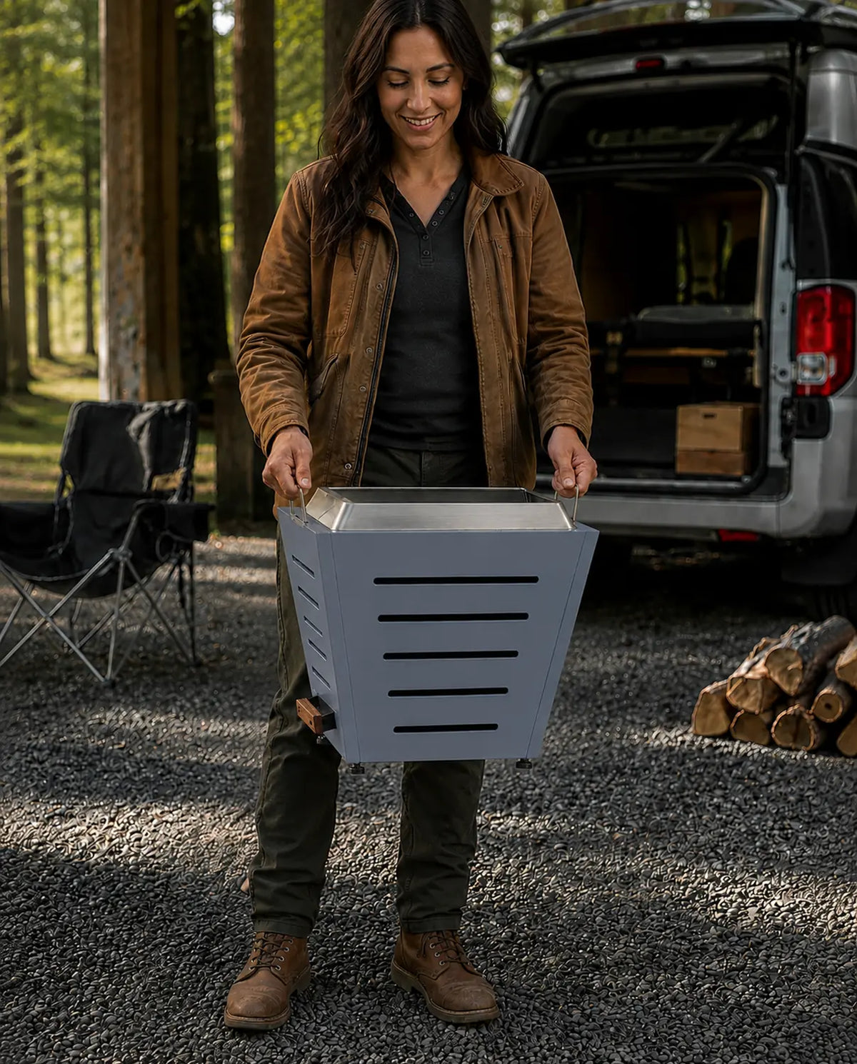 Woman carrying a Legacy Heating 20-inch Haze Blue slatted smokeless fire pit by its stainless steel side handles.