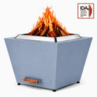 LEGACY HEATING 25 Inch Haze Blue Flat Smokeless Fire Pit with burning firewood, solid inverted-pyramid steel panels, a raised stainless steel fire ring, and a pull-out ash pan with a wooden handle.