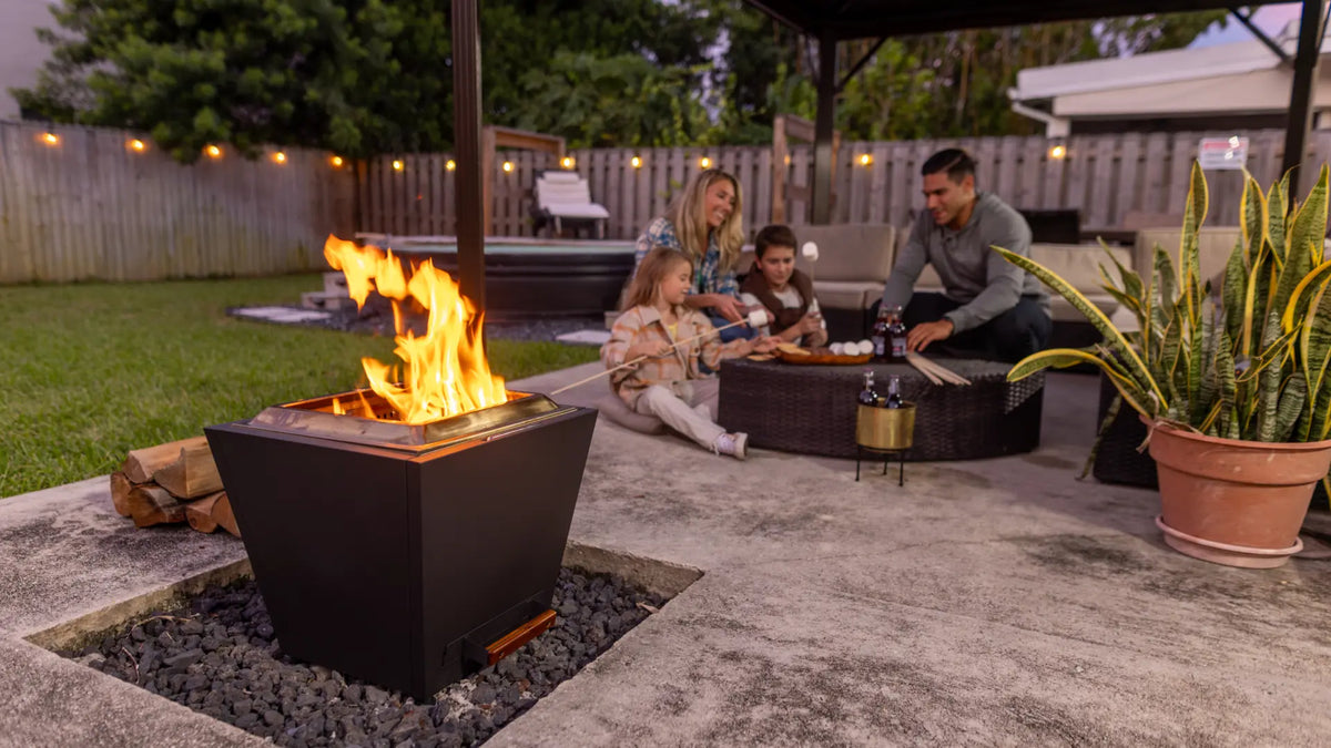 Family roasting marshmallows beside a Legacy Heating smokeless fire pit on a covered backyard patio.